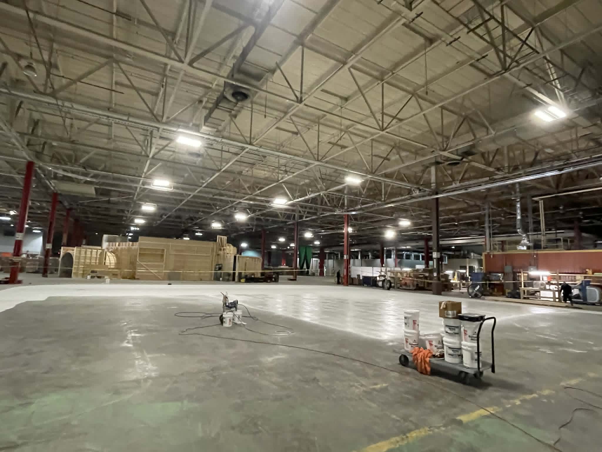 Large-scale industrial floor coating project by Carlson Painting Co. showing professional surface preparation and white high-durability finishes in an expansive warehouse.