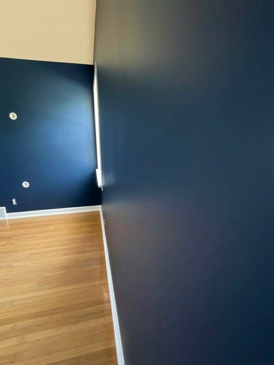 Professional high-sheen navy blue accent wall in a modern bedroom, showcasing flawless cinematic paint finish and precision cutting-in. Professional high-sheen navy blue accent wall in a modern bedroom, showcasing flawless cinematic paint finish and precision cutting-in.