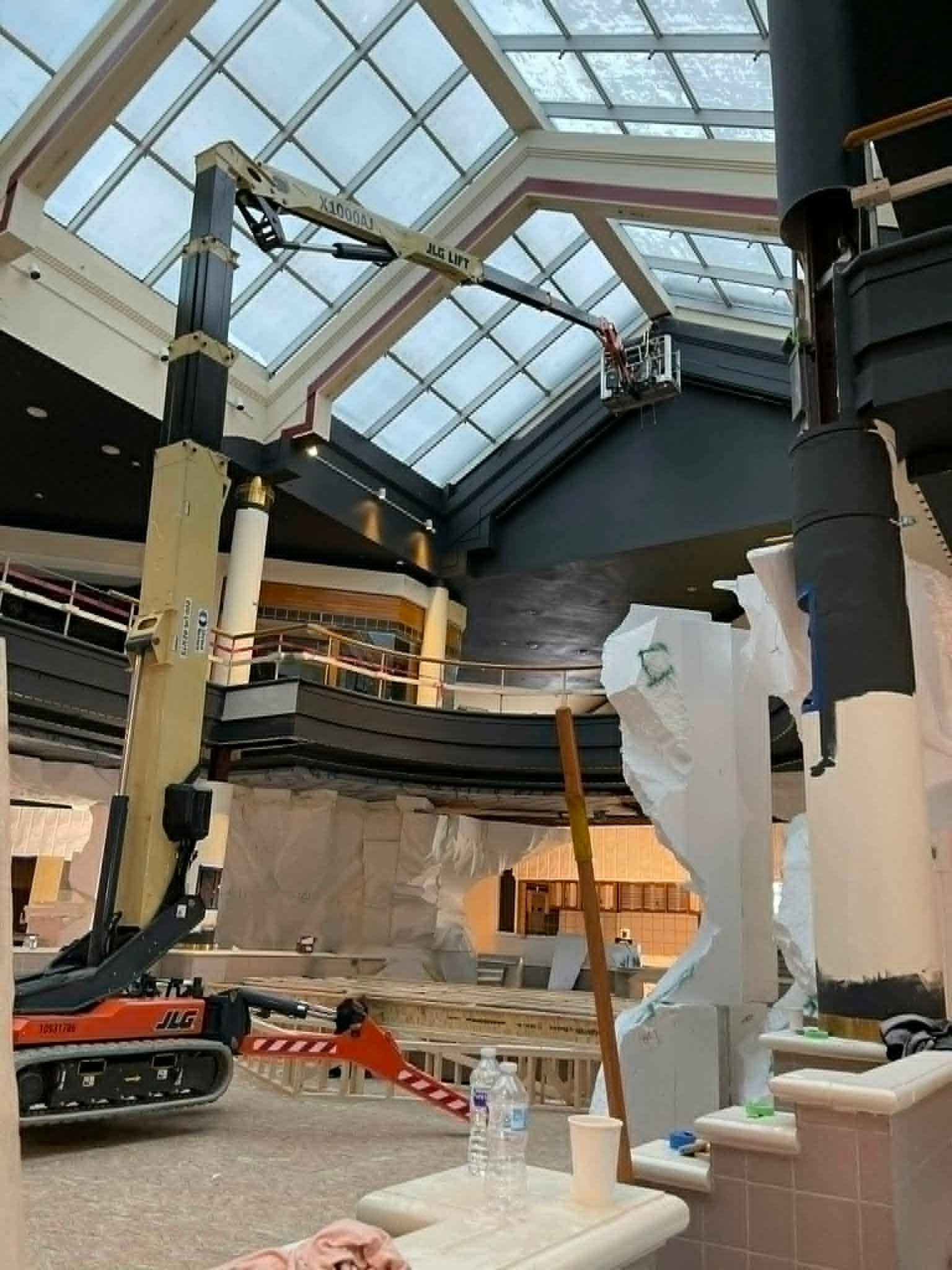 Carlson Painting Co. performing high-ceiling commercial interior painting using a JLG lift in a large atrium facility.